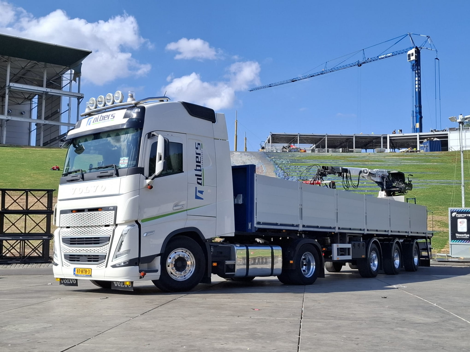 Witte Volvo-vrachtwagen van Albers Transport bij een bouwplaats met torenkraan